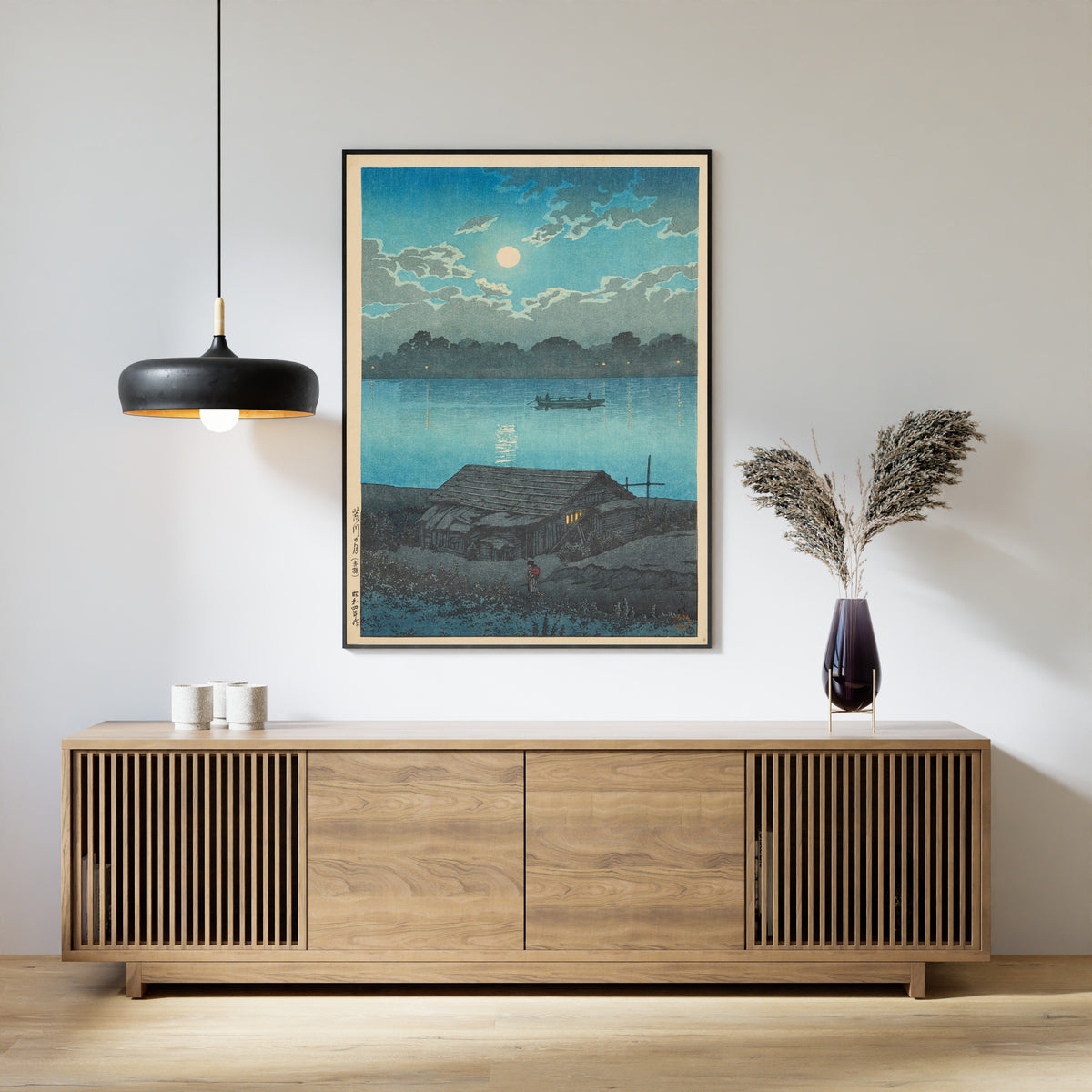 Framed art print of Moon on the Arakawa River in Akabane by Kawase Hasui, above a slatted wood sideboard