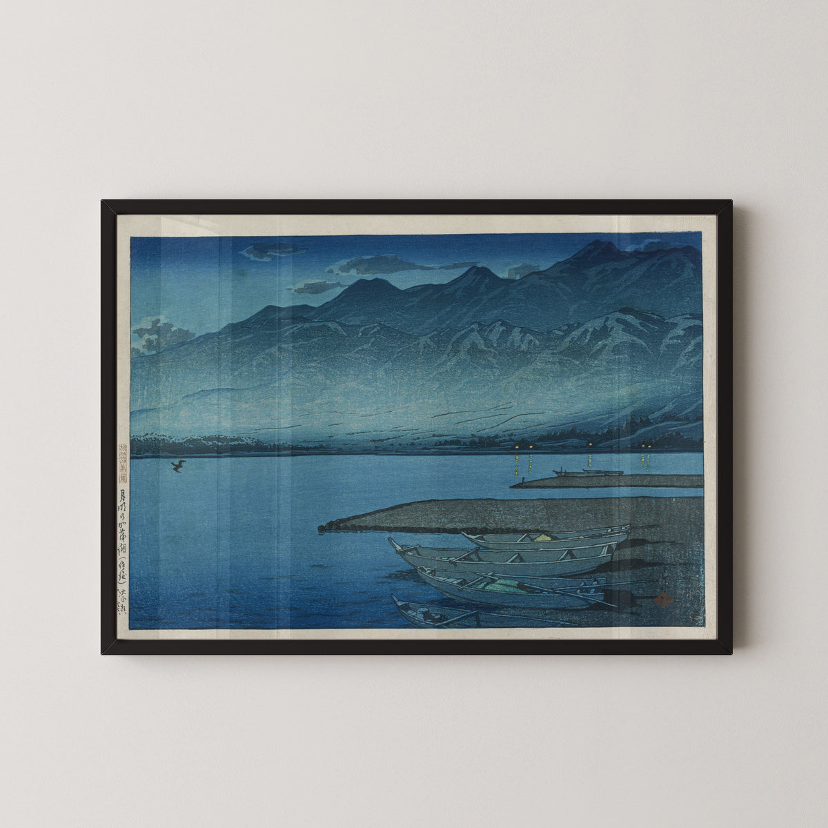Framed art print of Moonlight over Lake Kamo, Sado by Kawase Hasui, in a black frame on a pale wall
