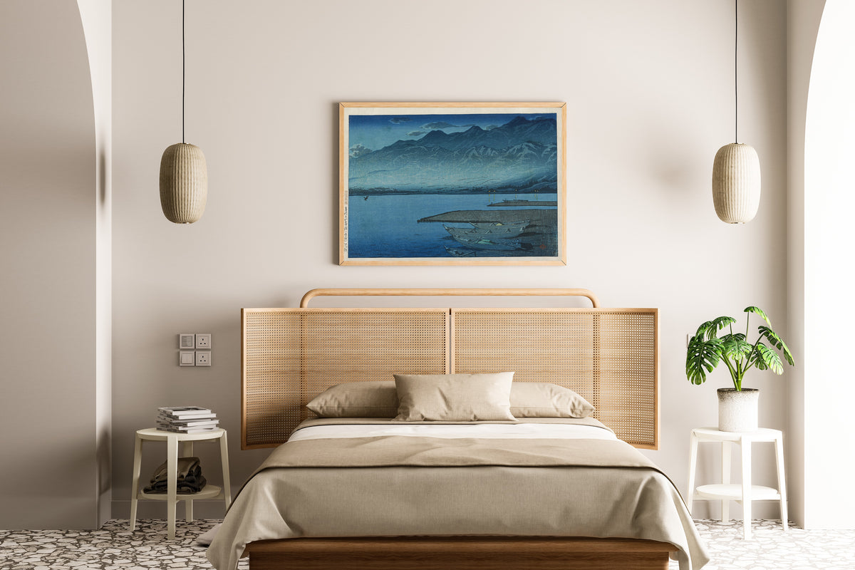 Framed art print of Moonlight over Lake Kamo, Sado by Kawase Hasui, above a cane-headboard bed
