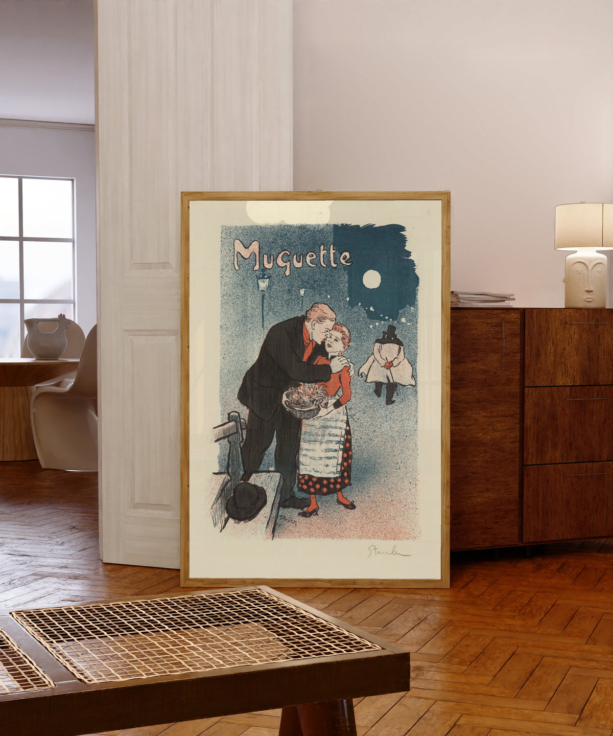 Framed art print of Muguette by Théophile Steinlen, in a light wood frame leaning in a warm room with a parquet floor