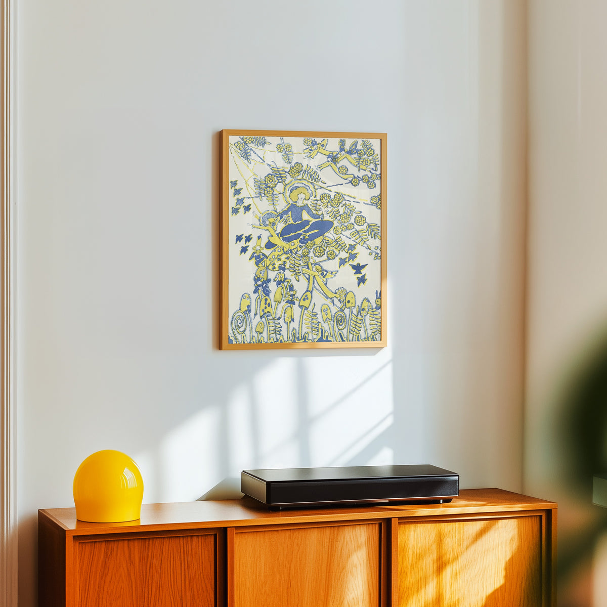 Framed art print of Mummy's Bedtime Story Book: Plate 7 by Jessie M. King, in a light wood frame on a white wall above an orange sideboard