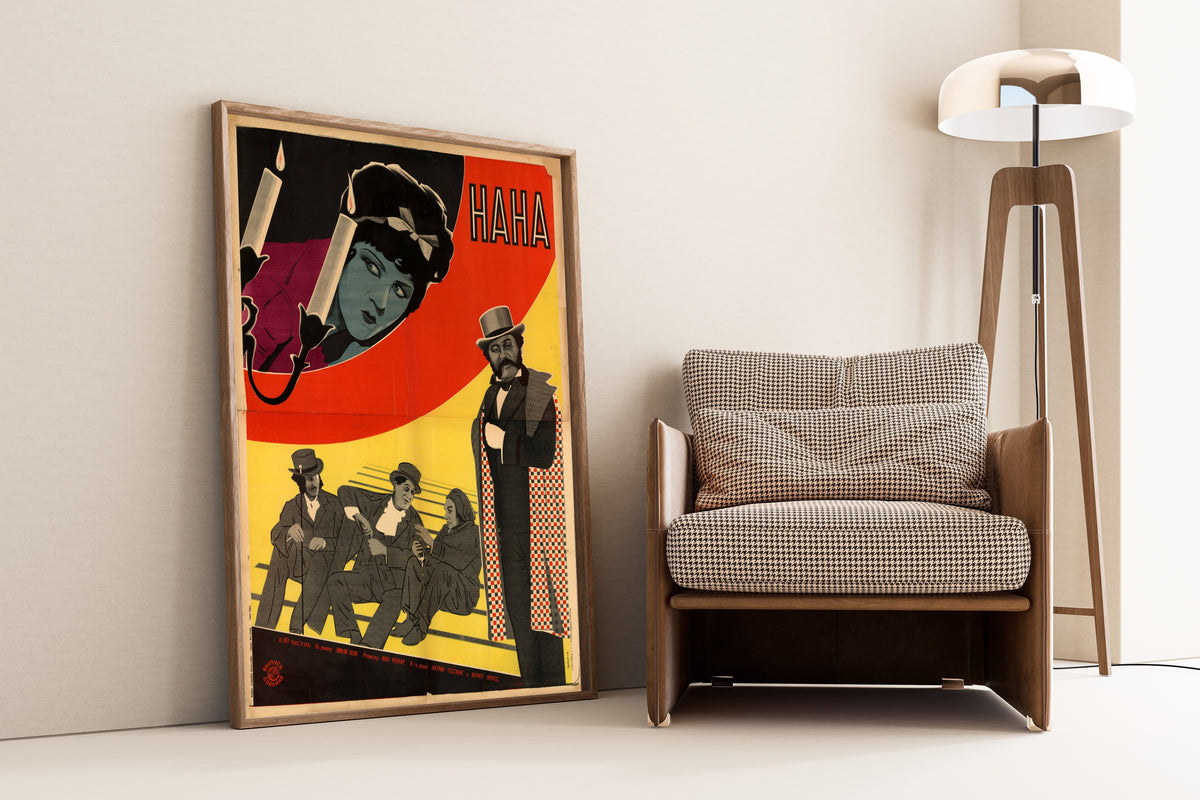 Framed art print of Nana, leaning against a wall beside an armchair and a floor lamp