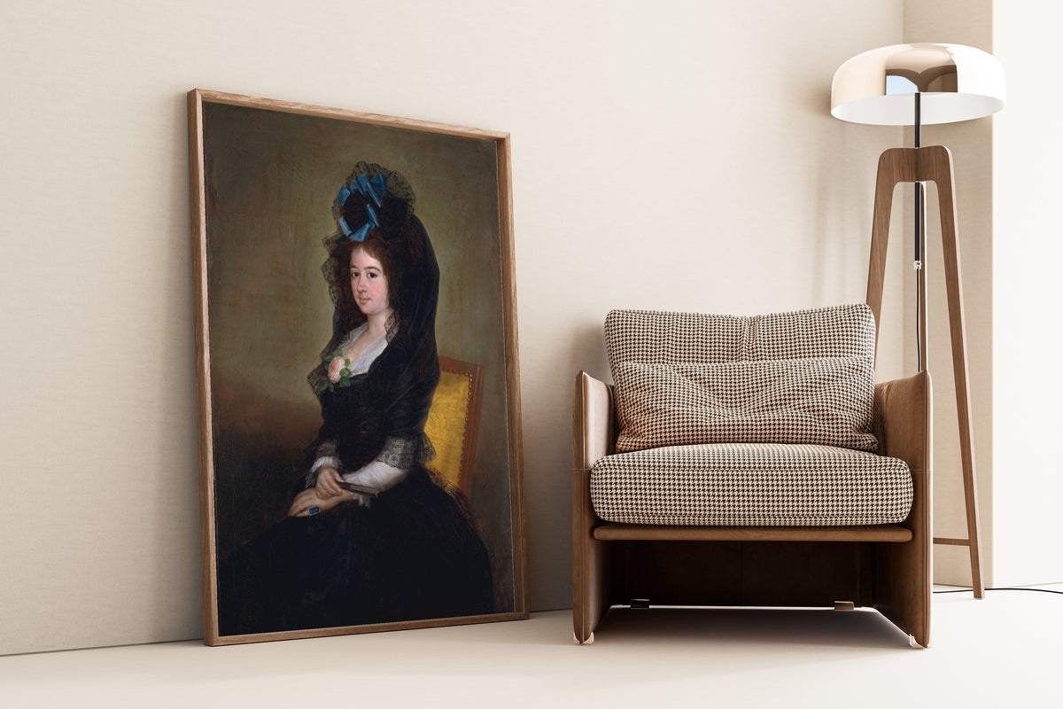 Framed art print of Narcisa Barañano Gayoso de Goicoechea by Francisco de Goya, leaning against a wall beside an armchair and a floor lamp