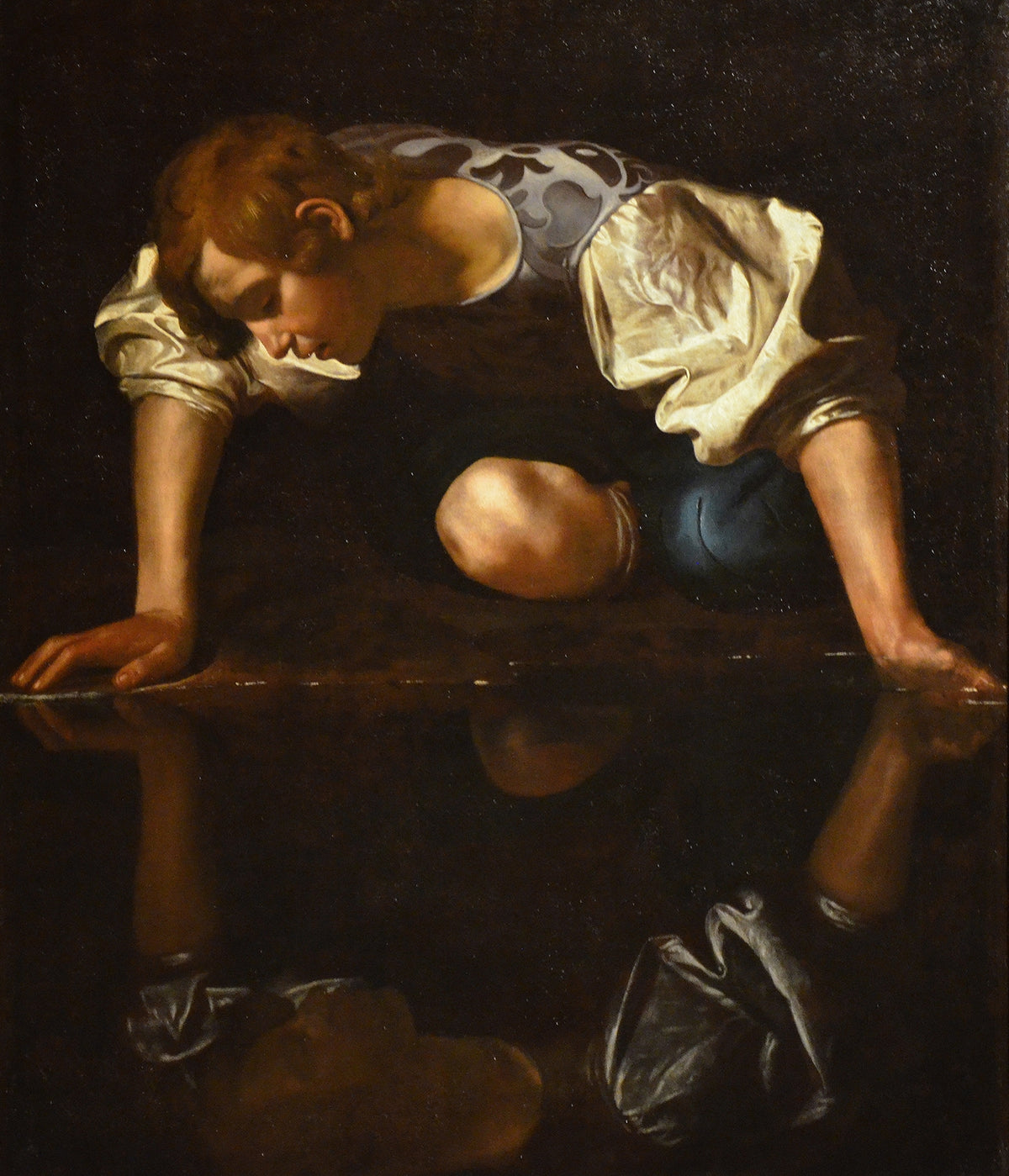 Narcissus by Caravaggio — A crouching youth bends to his reflection in still dark water
