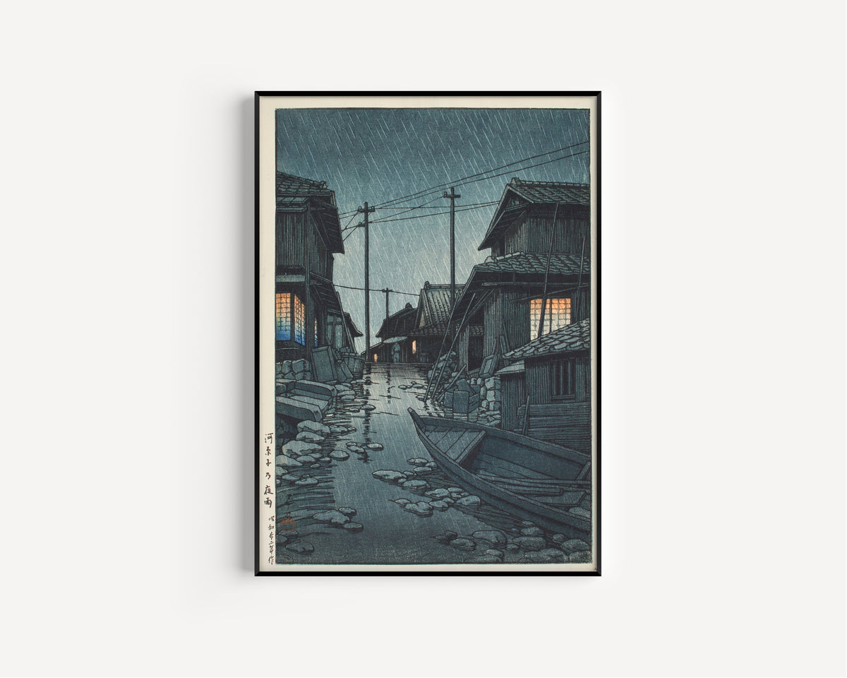 Framed art print of Night Rain at Kawarago by Kawase Hasui, in a slim black frame on a plain white wall