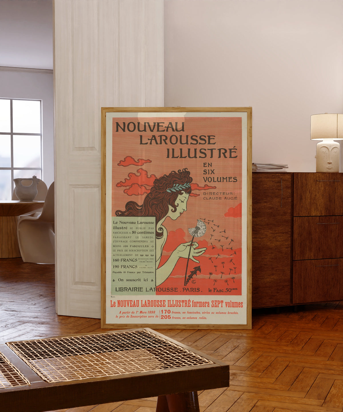 Framed art print of Nouveau Larousse Illustré by Eugène Grasset, in a light wood frame leaning in a warm room with a parquet floor