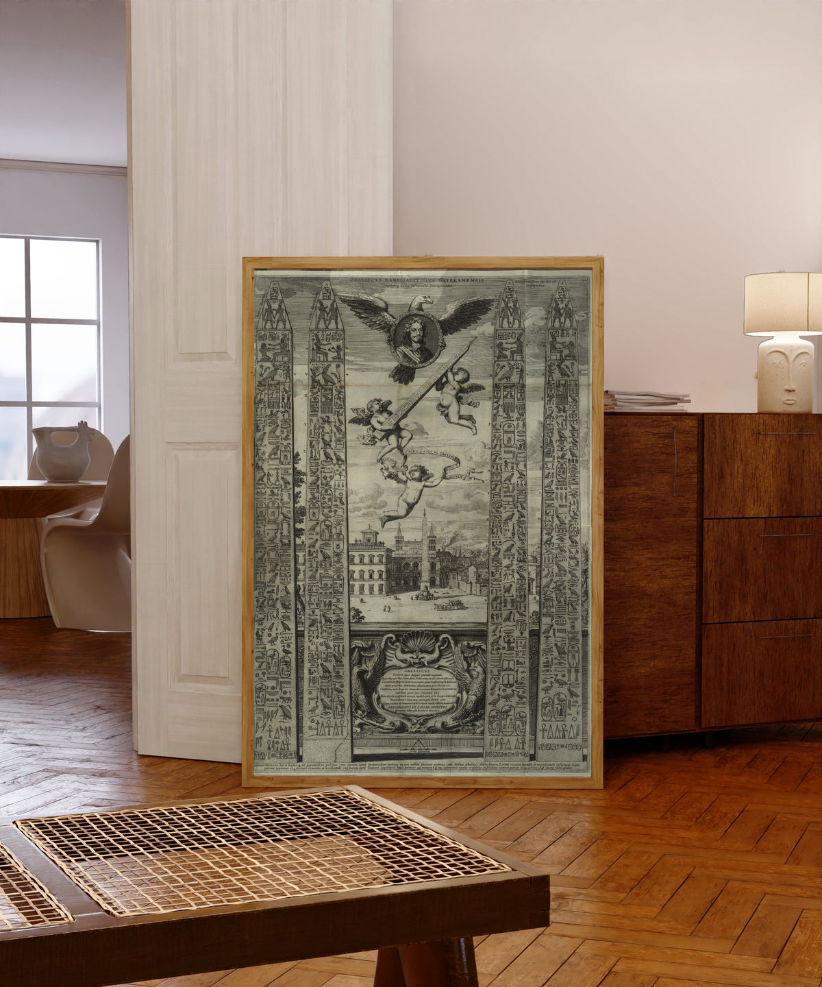 Framed art print of Obelisk Plate with Eagle and Cherubs (Oedipus… by Athanasius Kircher, in a light wood frame leaning in a warm room with a parquet floor