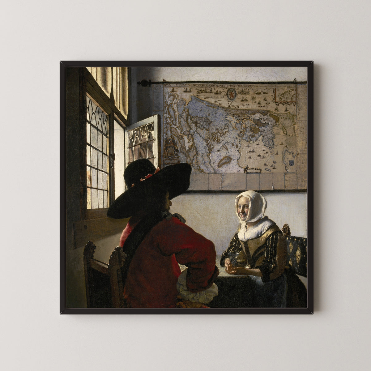 Framed art print of Officer and Laughing Girl by Johannes Vermeer, in a black frame on a pale wall