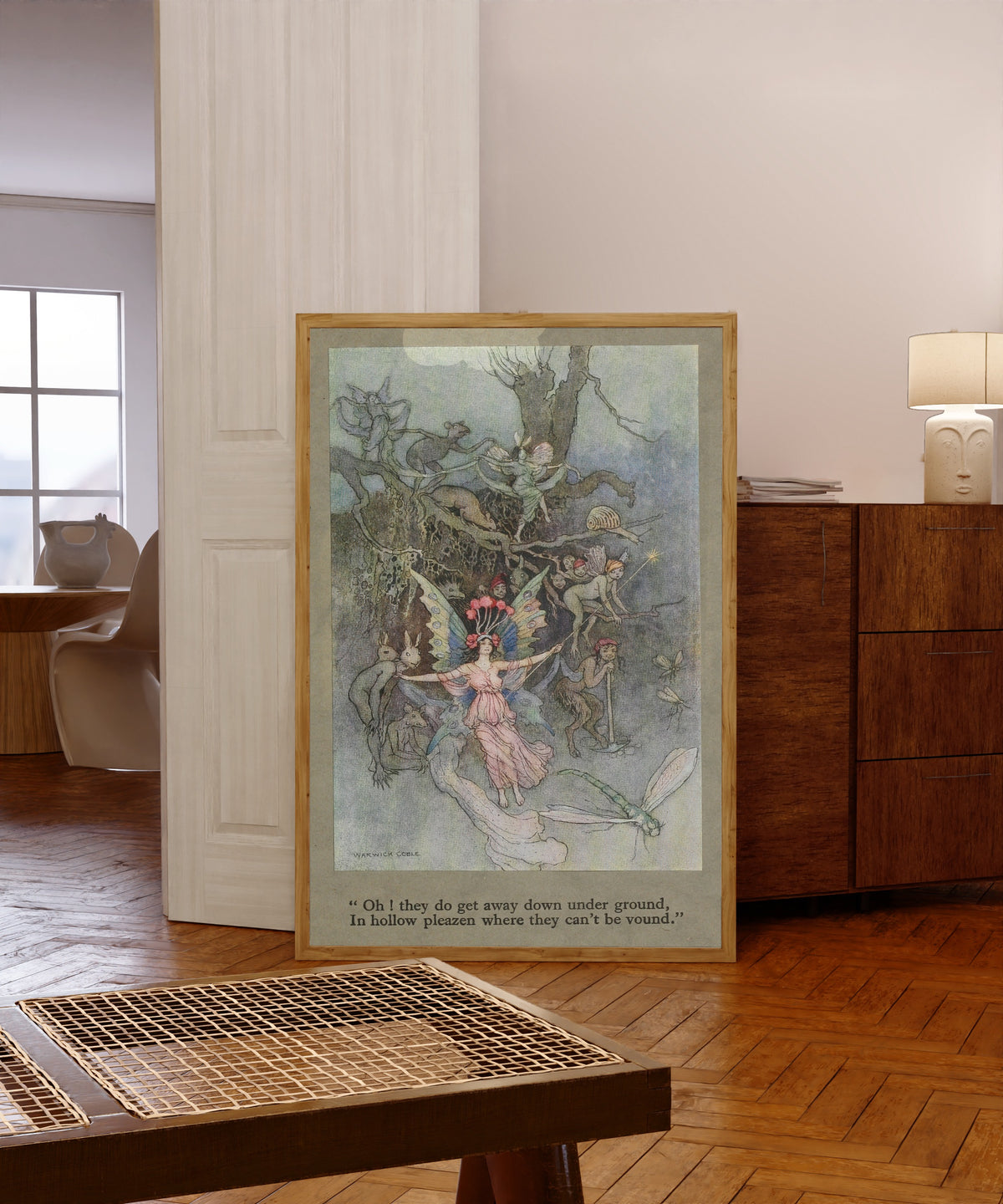 Framed art print of Oh! they do get away down under ground, in hollow… by Warwick Goble, in a light wood frame leaning in a warm room with a parquet floor