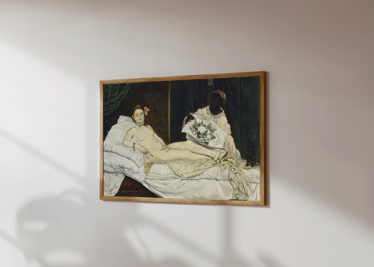 Framed art print of Olympia by Édouard Manet, in a light wood frame on a sunlit white wall, seen at a slight angle
