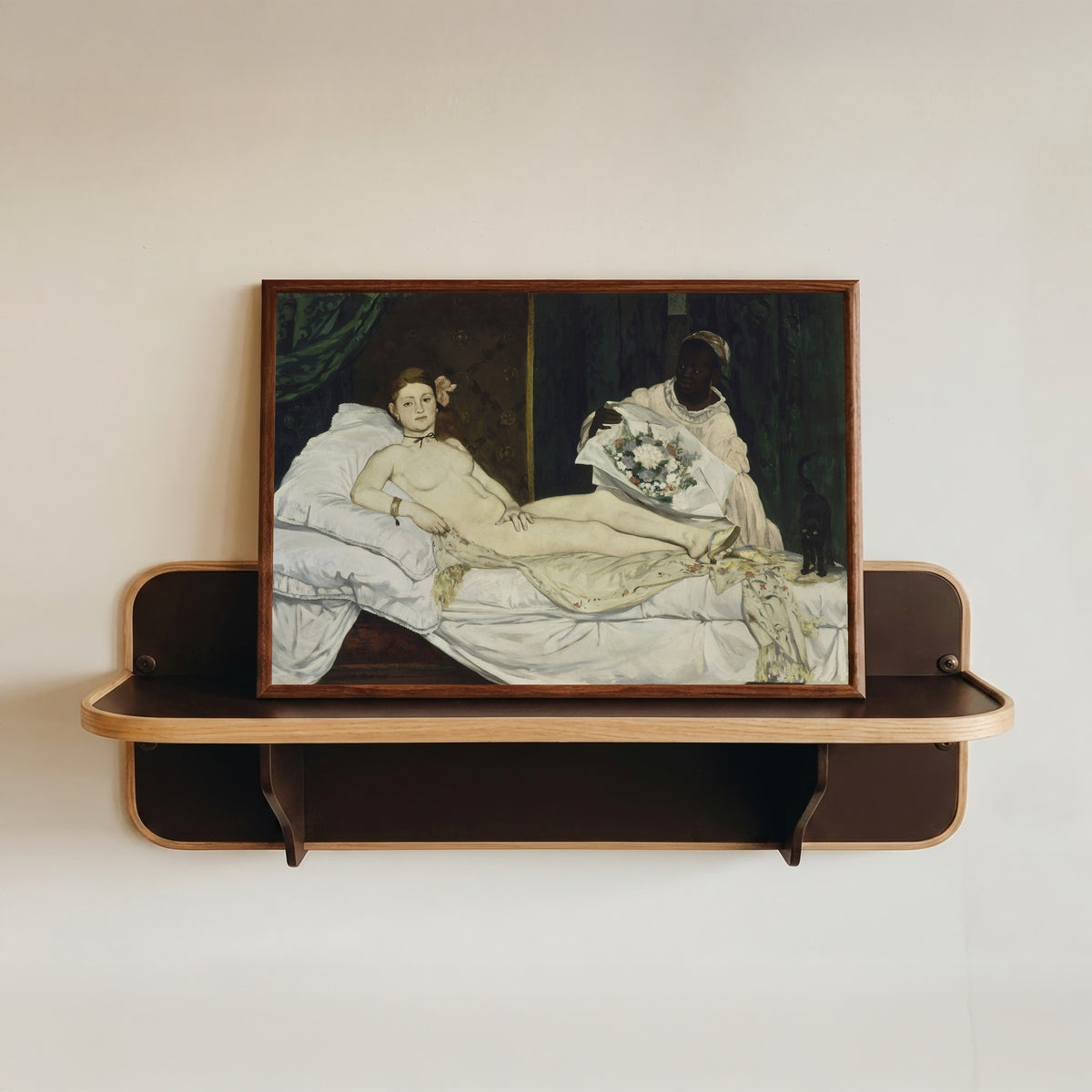 Framed art print of Olympia by Édouard Manet, in a dark wood frame resting on a wall shelf