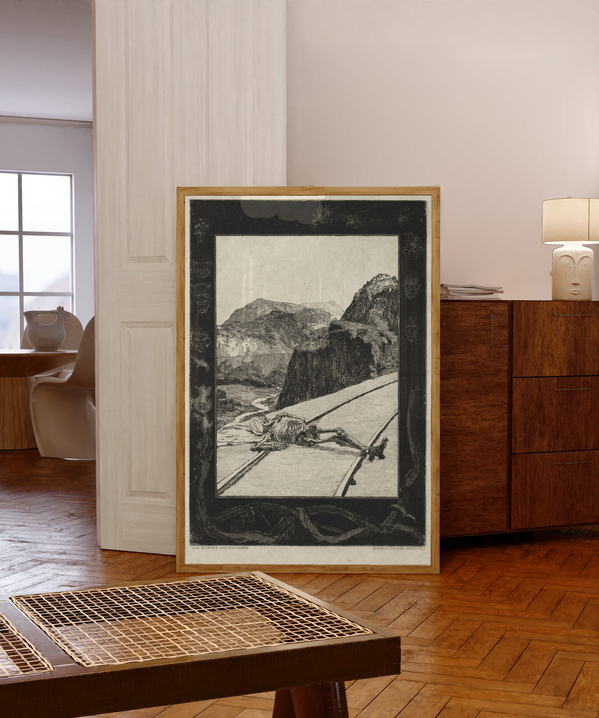 Framed art print of On Death I: On the Tracks by Max Klinger, in a light wood frame leaning in a warm room with a parquet floor