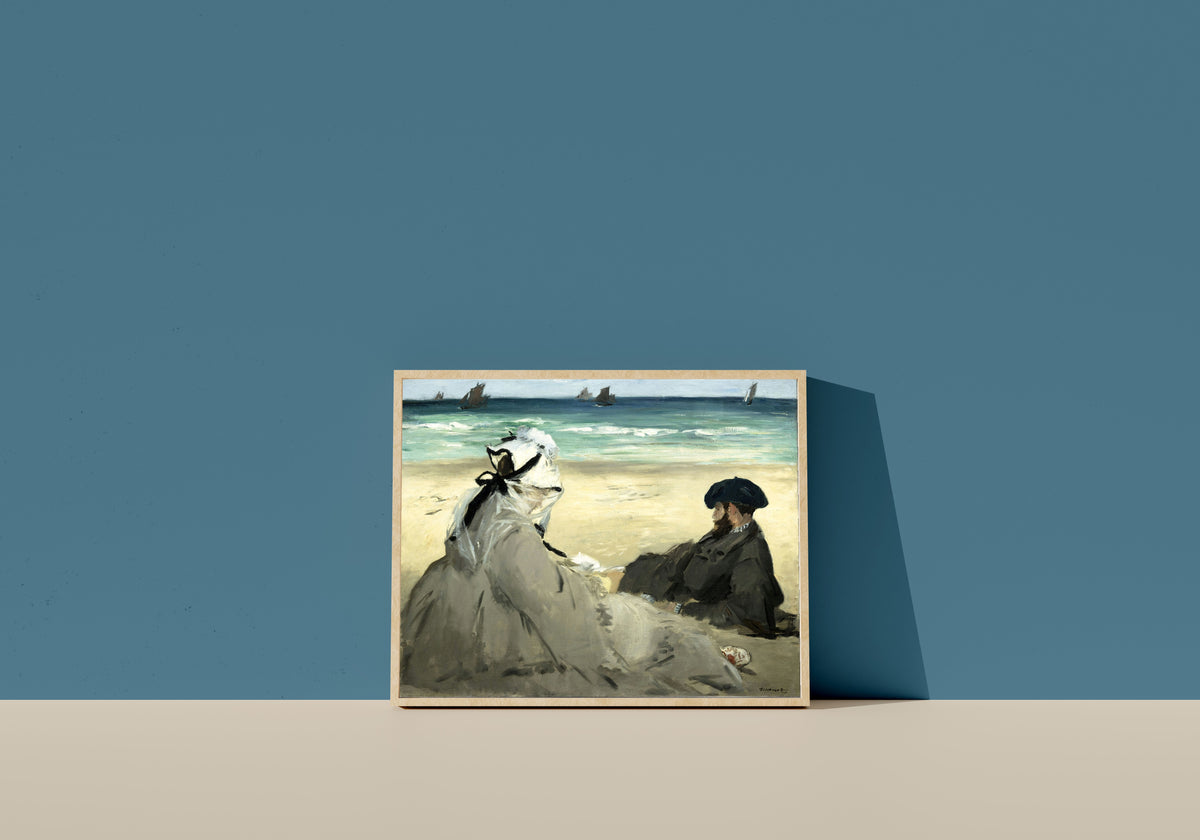 Framed art print of On the Beach by Édouard Manet, in a light wood frame leaning on a blue wall