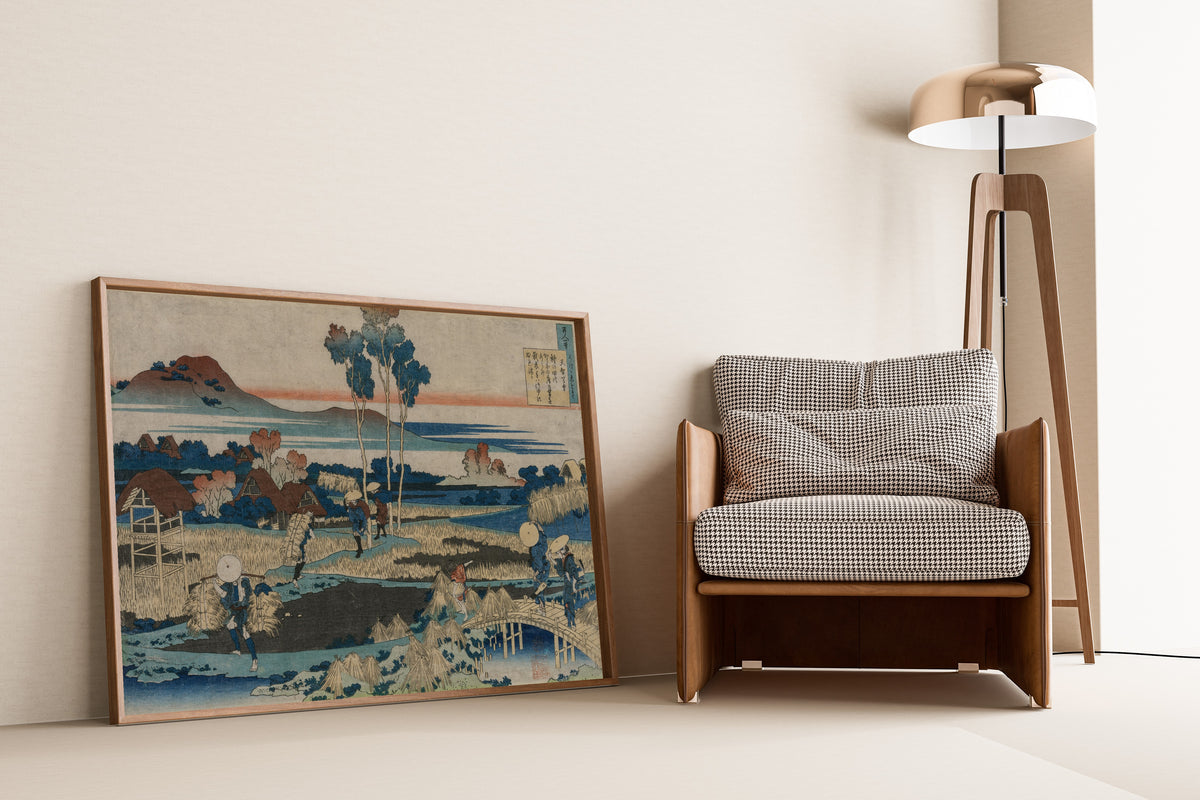 Framed art print of One Hundred Poems Explained by the Nurse: Poem by… by Katsushika Hokusai, leaning against a wall beside an armchair and a floor lamp