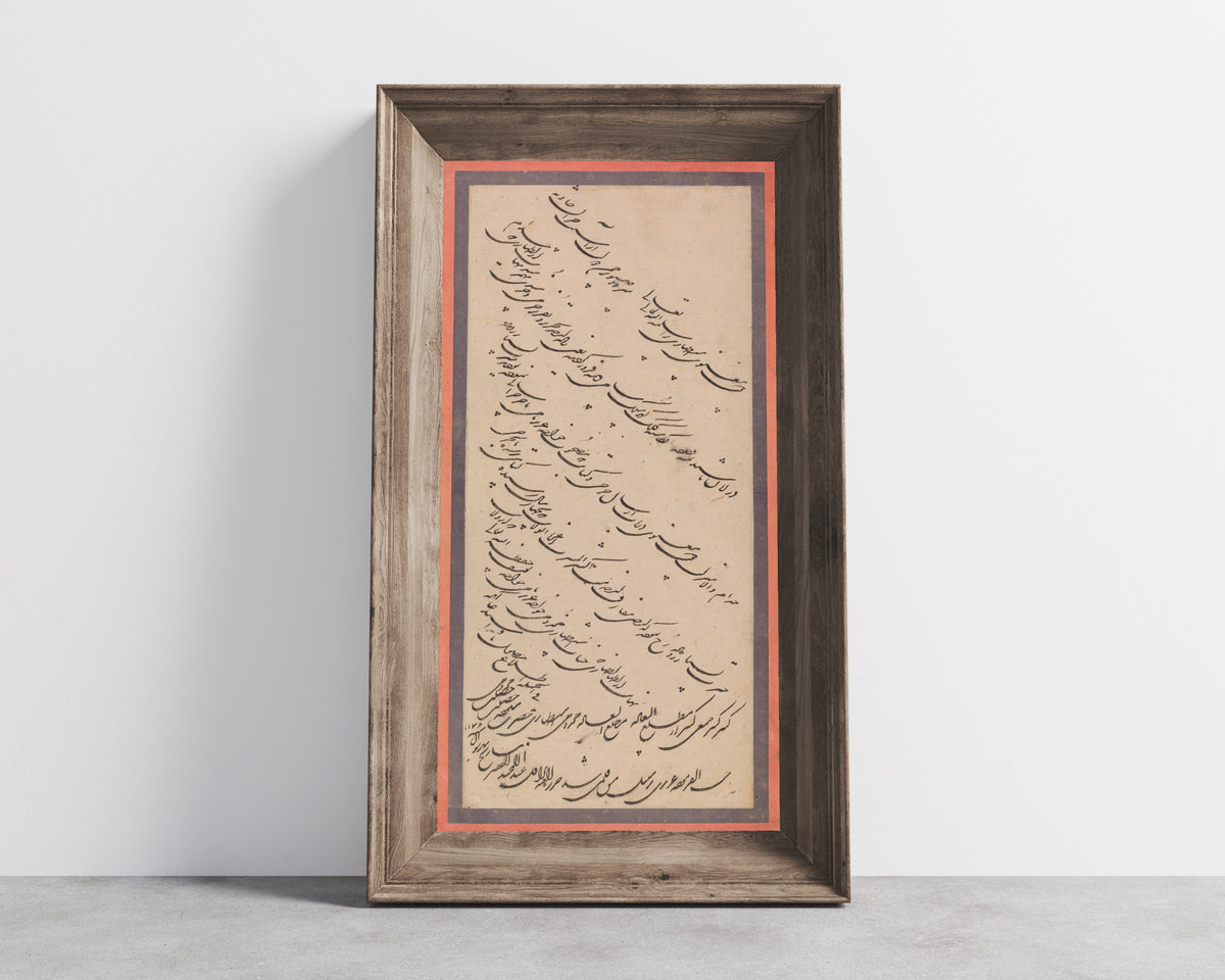 Framed art print of Page of Calligraphy by Abd al-Majid Taleqani, in a wide wooden frame leaning against a concrete wall