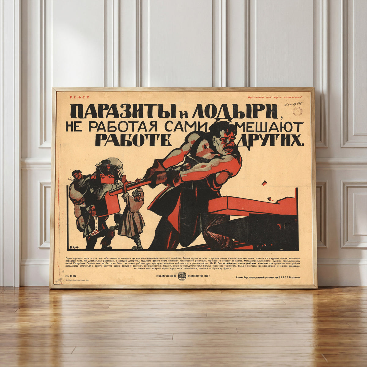 Framed art print of Parasites and Idlers, by Not Working, Themselves… by Vasily Kostyanitsyn, in a light wood frame leaning against a panelled white wall