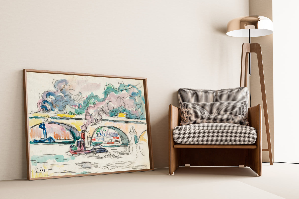 Framed art print of Paris, Le Pont-Royal by Paul Signac, leaning against a wall beside an armchair and a floor lamp