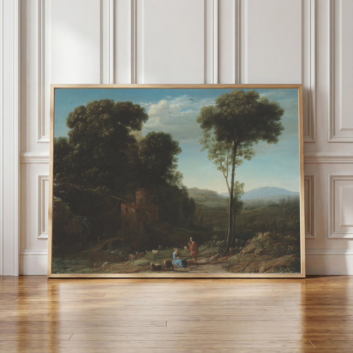 Framed art print of Pastoral Landscape with a Mill by Claude Lorrain, in a light wood frame leaning against a panelled white wall