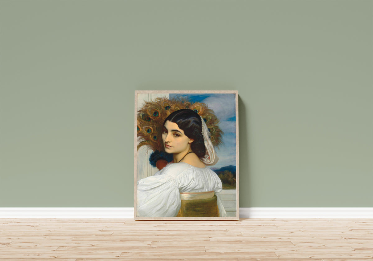Framed art print of Pavonia by Frederic Leighton, in a light wood frame leaning on a sage green wall above a wooden floor
