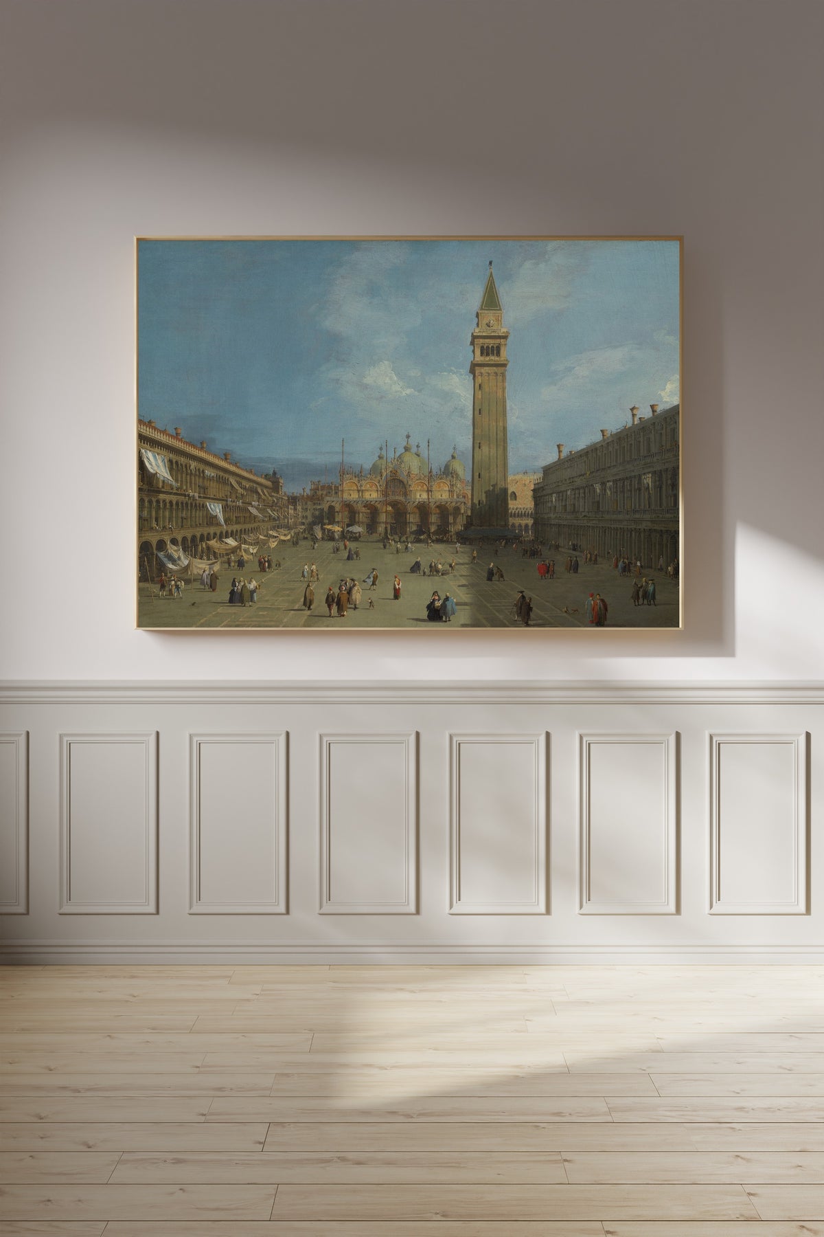 Framed art print of Piazza San Marco by Canaletto, on a panelled wall in afternoon light