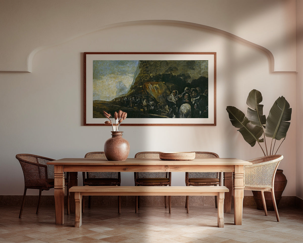 Framed art print of Pilgrimage to the Fountain of San Isidro by Francisco de Goya, above a wooden dining table