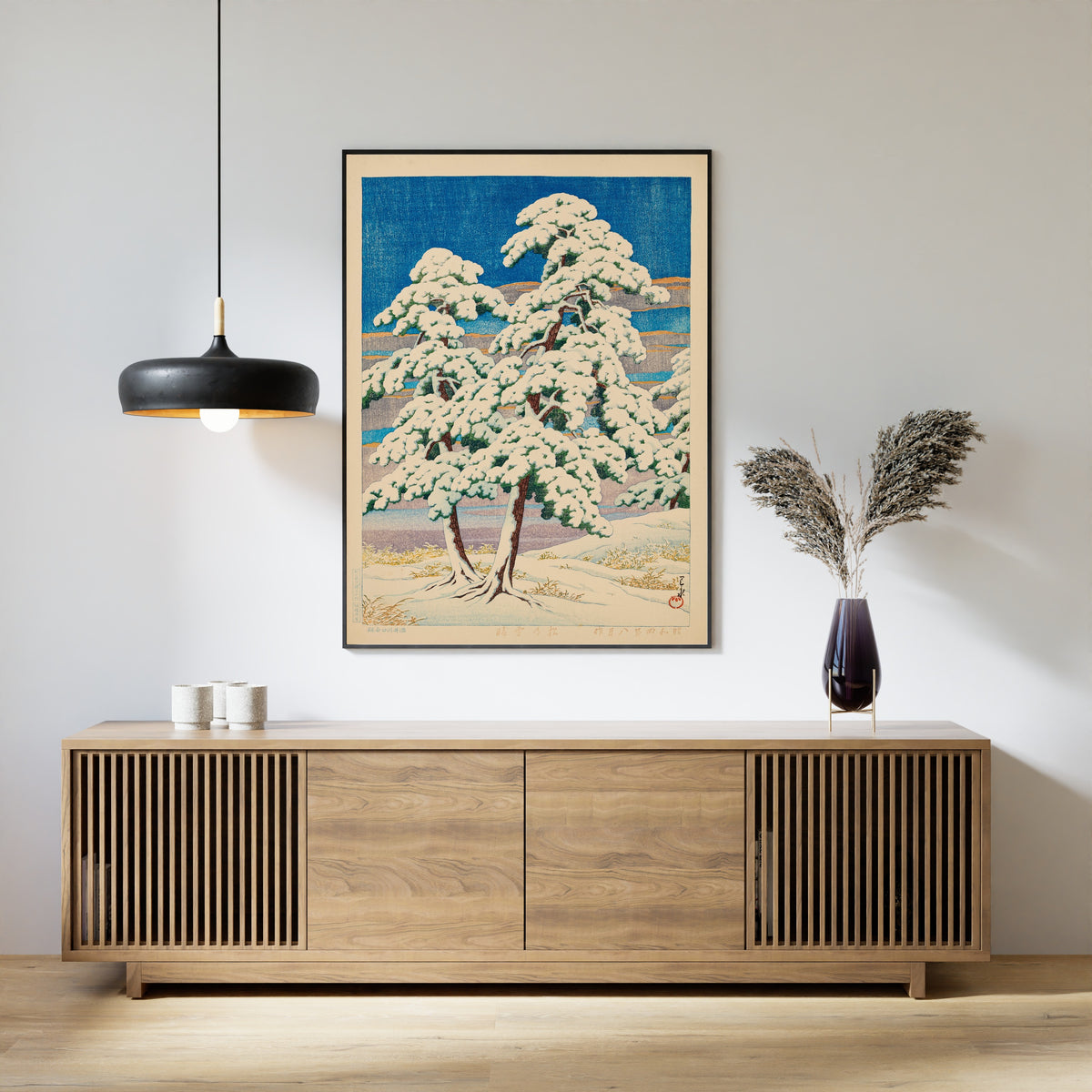 Framed art print of Pines in Clear Weather After Snow by Kawase Hasui, above a slatted wood sideboard
