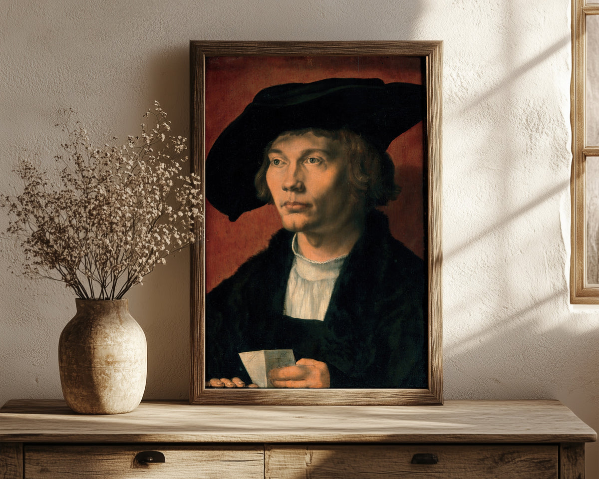 Framed art print of Portrait of Bernhart von Reesen by Albrecht Dürer, in a dark wood frame leaning on a rustic console beside dried flowers