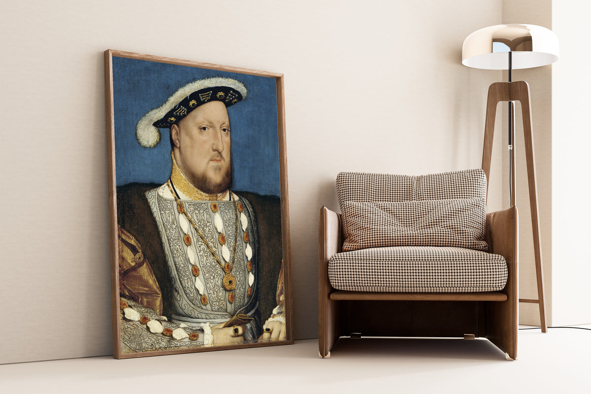 Framed art print of Portrait of Henry VIII by Hans Holbein the Younger, leaning against a wall beside an armchair and a floor lamp