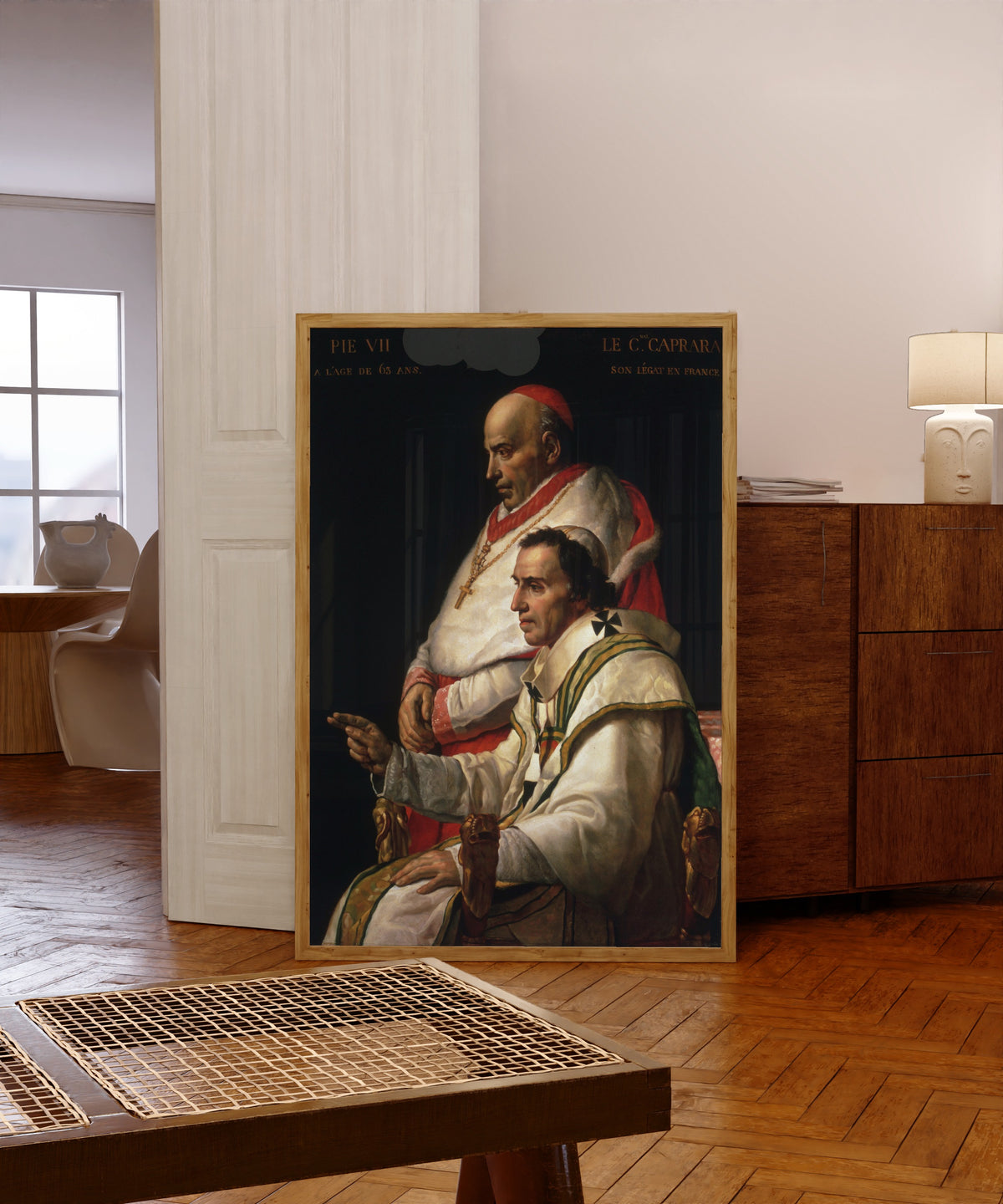 Framed art print of Portrait of Pope Pius VII and Cardinal Caprara by Jacques-Louis David, in a light wood frame leaning in a warm room with a parquet floor