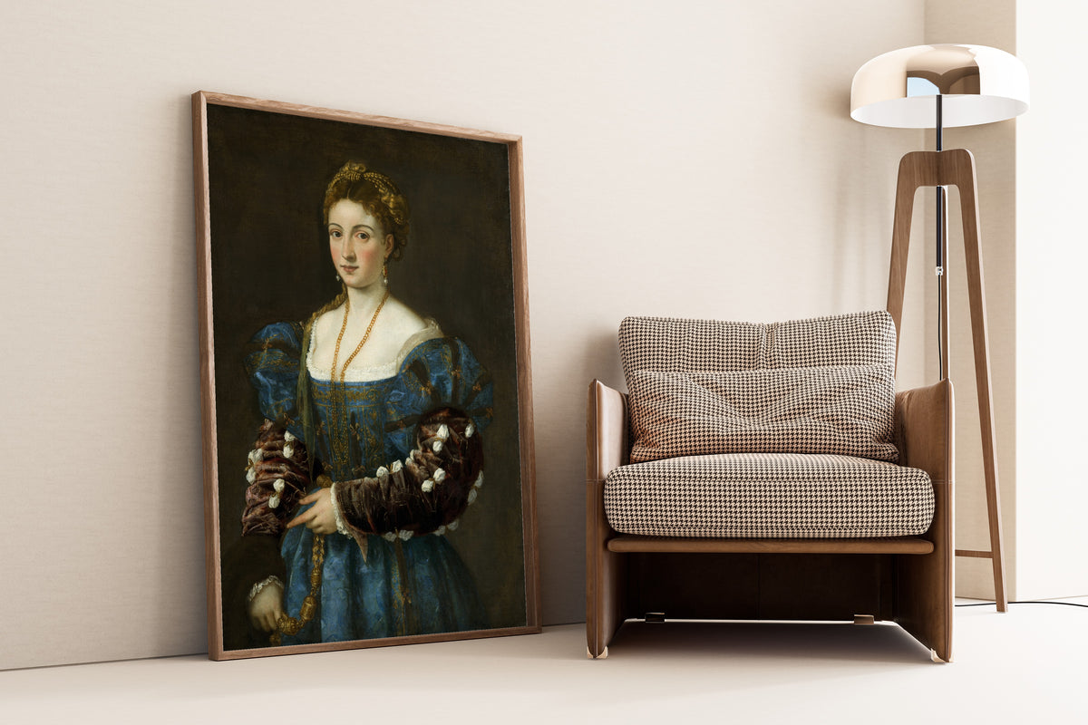 Framed art print of Portrait of a Lady (La Bella) by Titian, leaning against a wall beside an armchair and a floor lamp