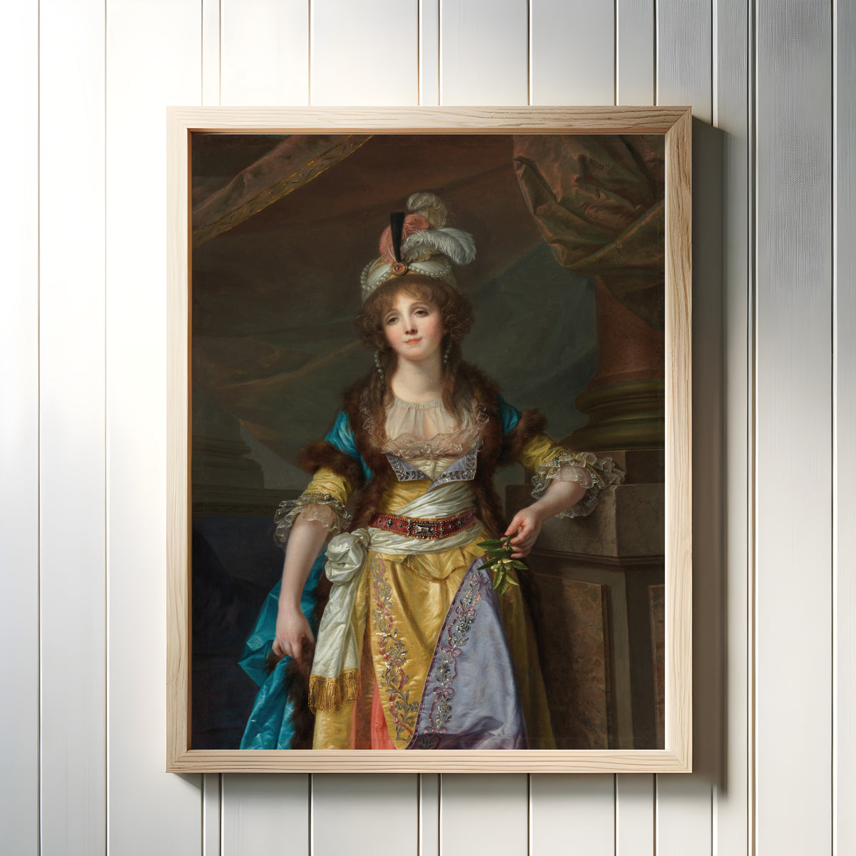 Framed art print of Portrait of a Lady in Turkish Fancy Dress by Jean-Baptiste Greuze, in a light wood frame on a white panelled wall