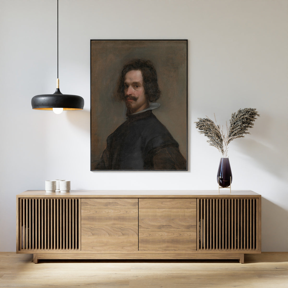 Framed art print of Portrait of a Man, Possibly a Self-Portrait by Diego Velázquez, above a slatted wood sideboard