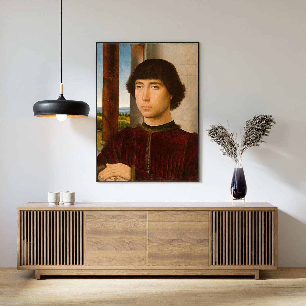 Framed art print of Portrait of a Young Man by Hans Memling, above a slatted wood sideboard