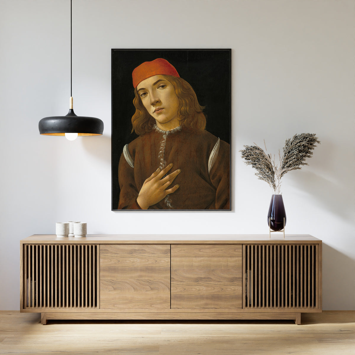 Framed art print of Portrait of a Youth by Sandro Botticelli, above a slatted wood sideboard