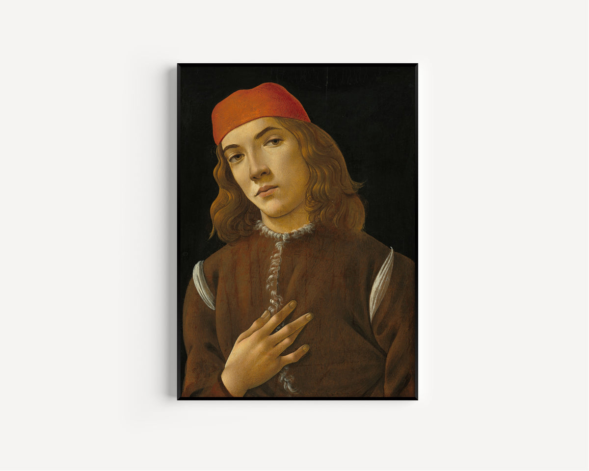 Framed art print of Portrait of a Youth by Sandro Botticelli, in a slim black frame on a plain white wall
