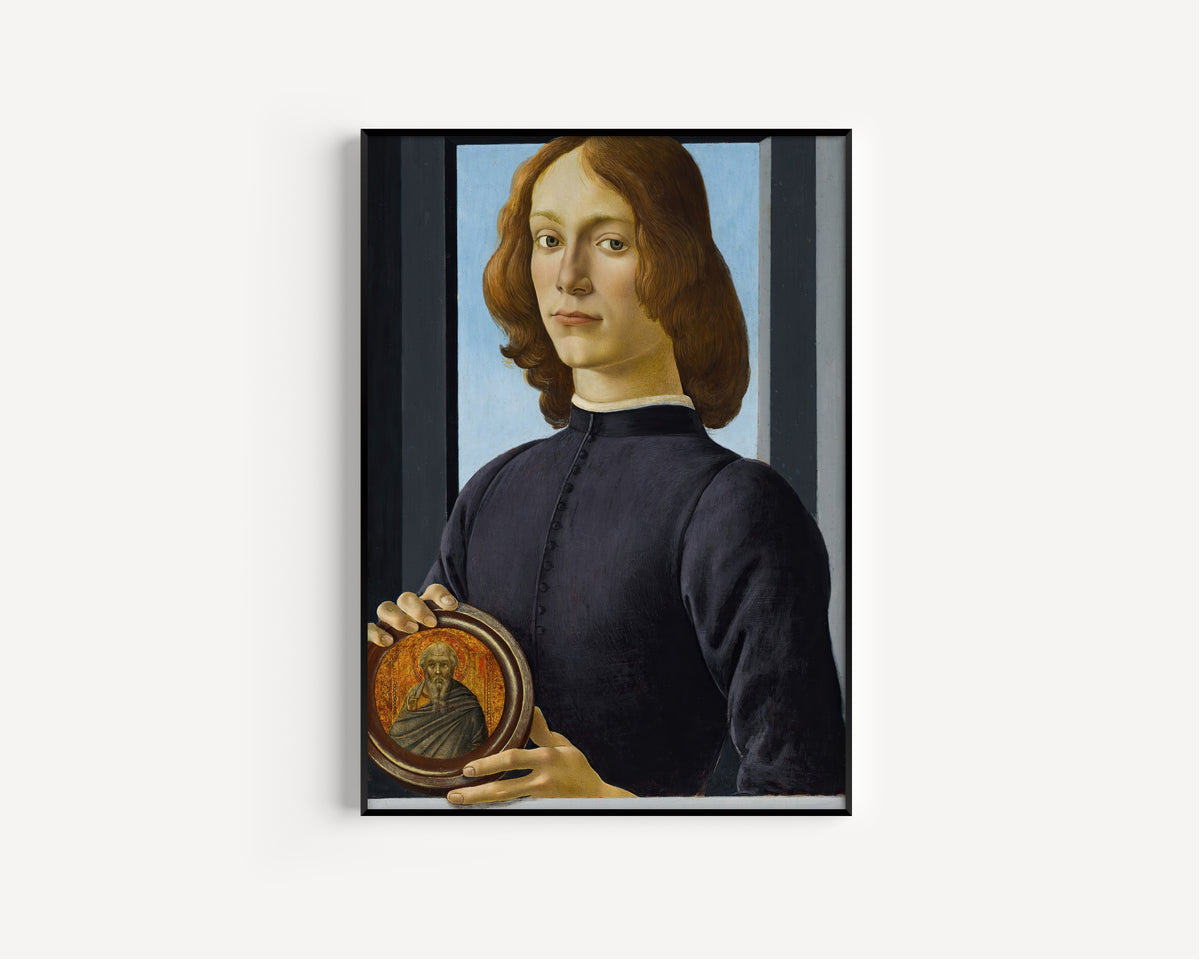 Framed art print of Portrait of a young man holding a roundel by Sandro Botticelli, in a slim black frame on a plain white wall