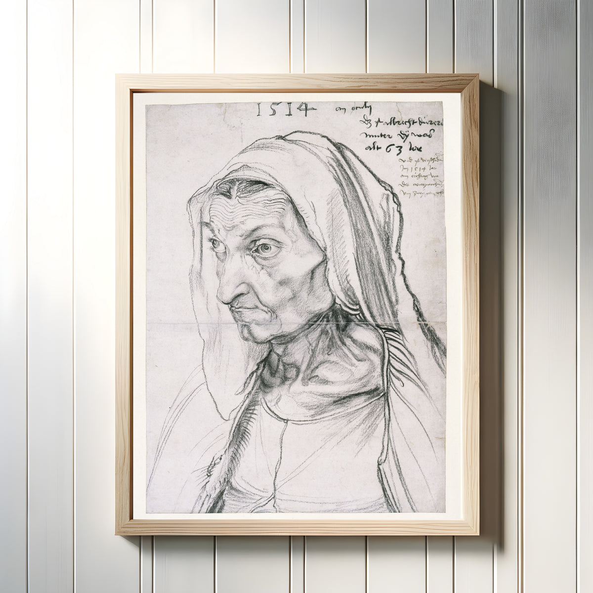Framed art print of Portrait of the Artist's Mother at the Age of 63 by Albrecht Dürer, in a light wood frame on a white panelled wall