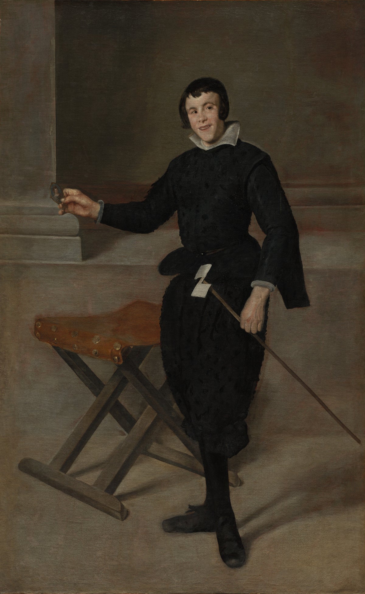 Portrait of the Jester Calabazas by Diego Velázquez — A smiling jester in black stands beside a folding stool