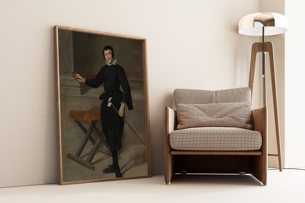 Framed art print of Portrait of the Jester Calabazas by Diego Velázquez, leaning against a wall beside an armchair and a floor lamp