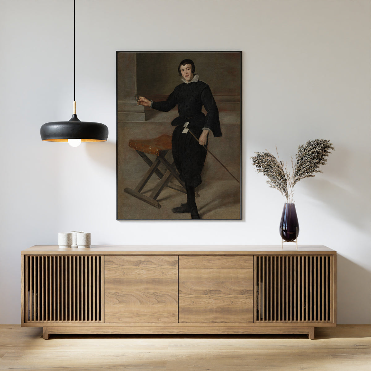Framed art print of Portrait of the Jester Calabazas by Diego Velázquez, above a slatted wood sideboard