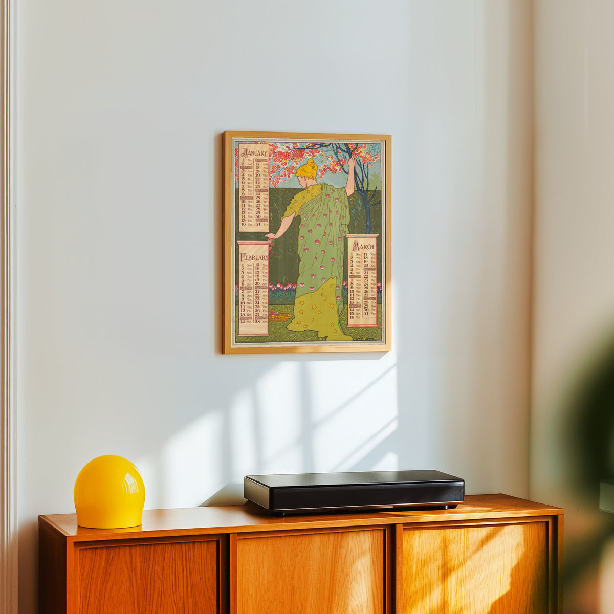 Framed art print of Poster Calendar for 1897: January, February, March by Louis Rhead, in a light wood frame on a white wall above an orange sideboard