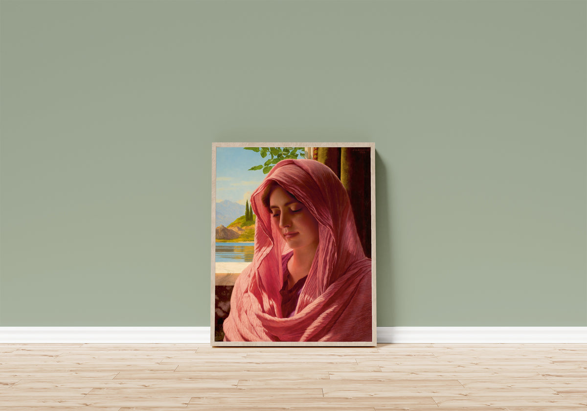 Framed art print of Pyrallis by John William Godward, in a light wood frame leaning on a sage green wall above a wooden floor