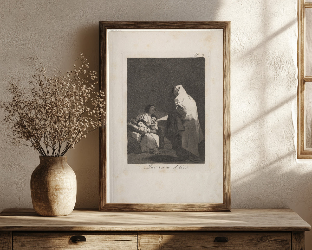 Framed art print of Que viene el Coco (Here Comes the Bogeyman)… by Francisco de Goya, in a dark wood frame leaning on a rustic console beside dried flowers