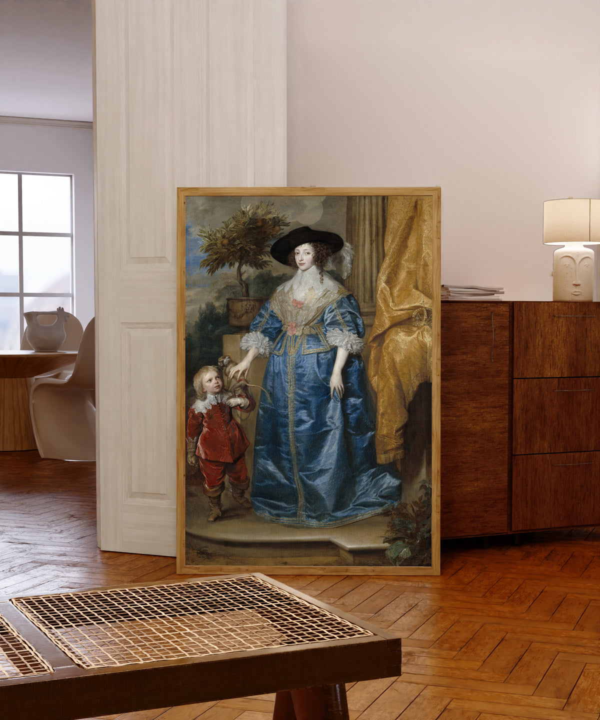 Framed art print of Queen Henrietta Maria with Sir Jeffrey Hudson by Anthony van Dyck, in a light wood frame leaning in a warm room with a parquet floor