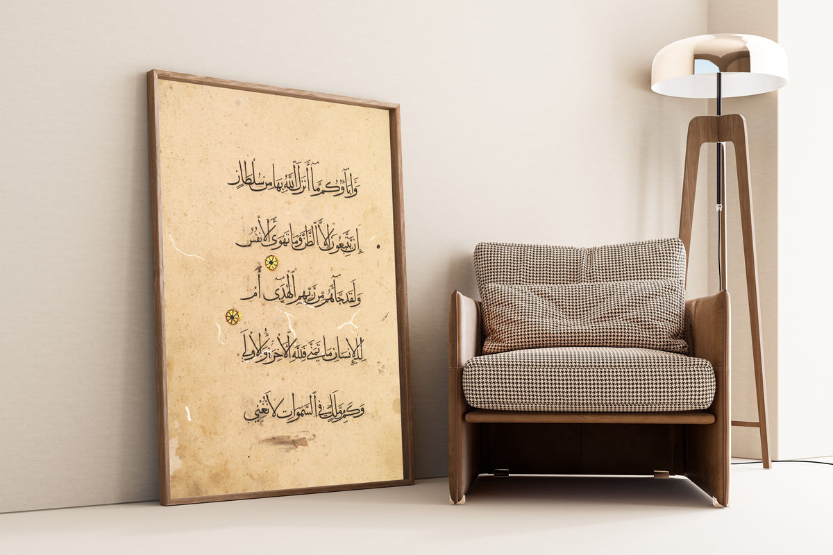Framed art print of Qur'an Folio: Sura al-Najm (Left Page), leaning against a wall beside an armchair and a floor lamp