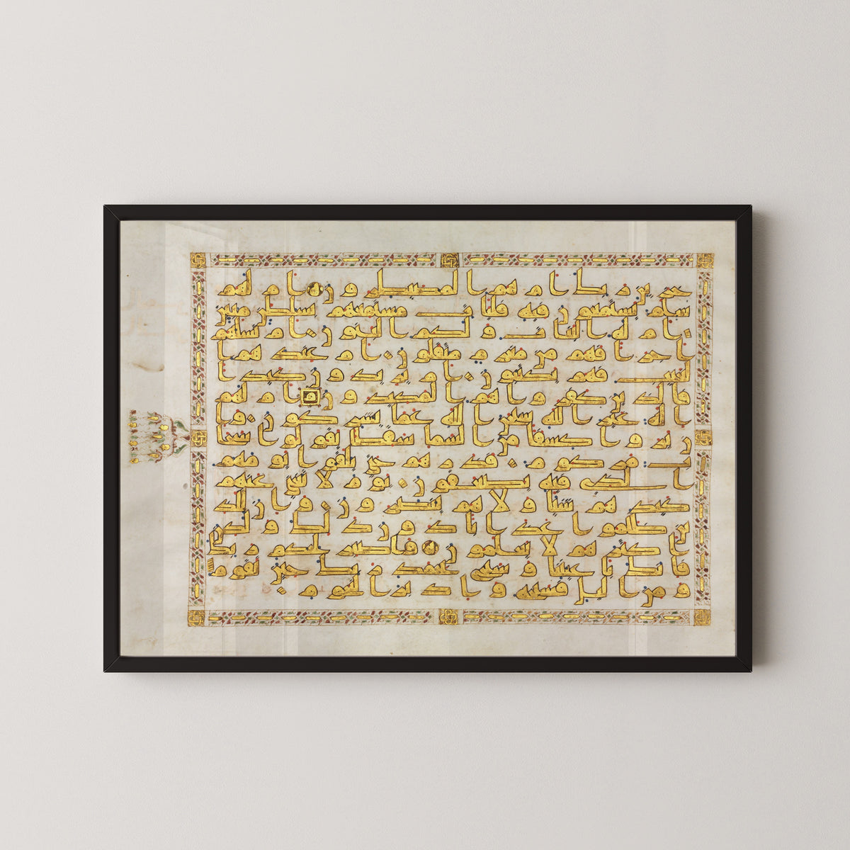 Framed art print of Qur'an Folio: Sura al-Tur (Gold Kufic), in a black frame on a pale wall