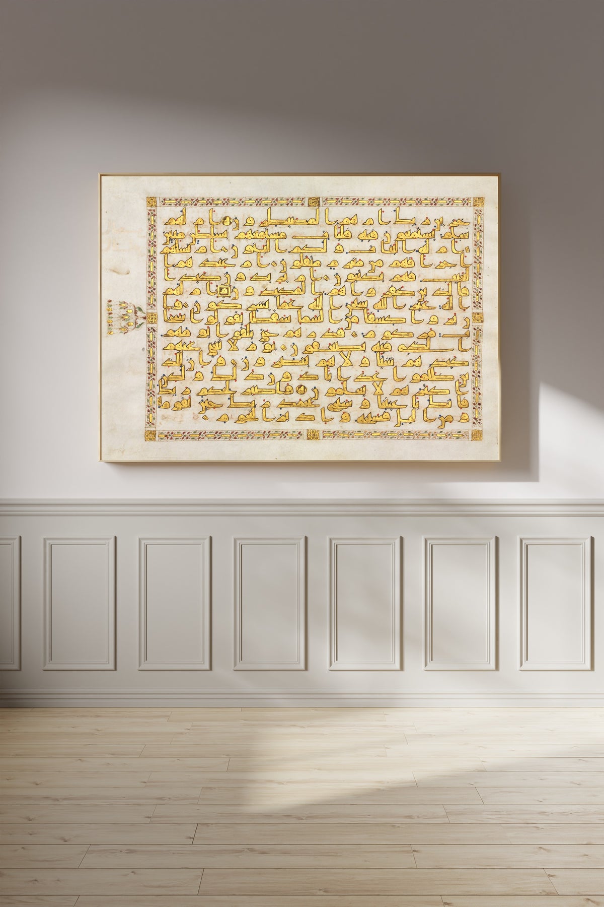 Framed art print of Qur'an Folio: Sura al-Tur (Gold Kufic), on a panelled wall in afternoon light