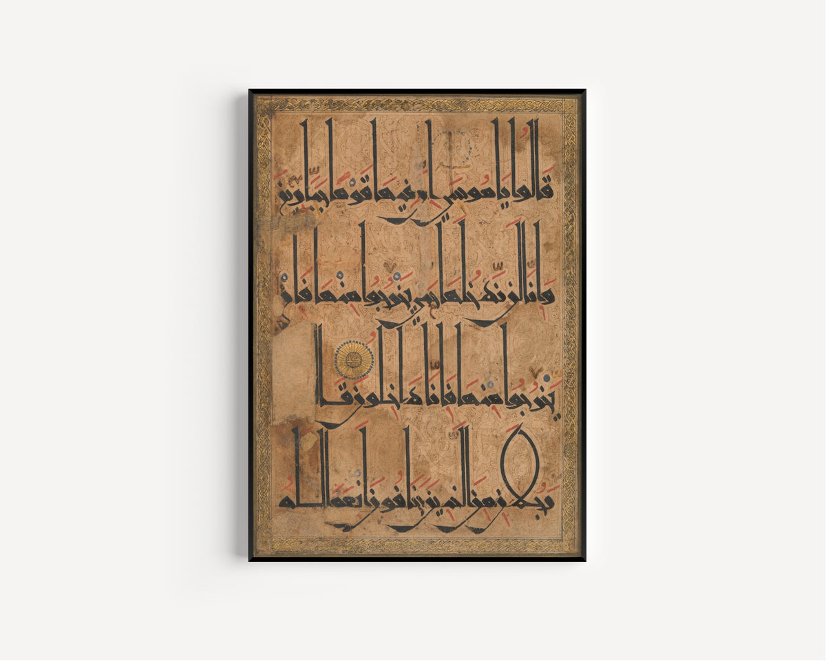 Framed art print of Qur'an Folio (Gold Roundel on Arabesque Ground), in a slim black frame on a plain white wall