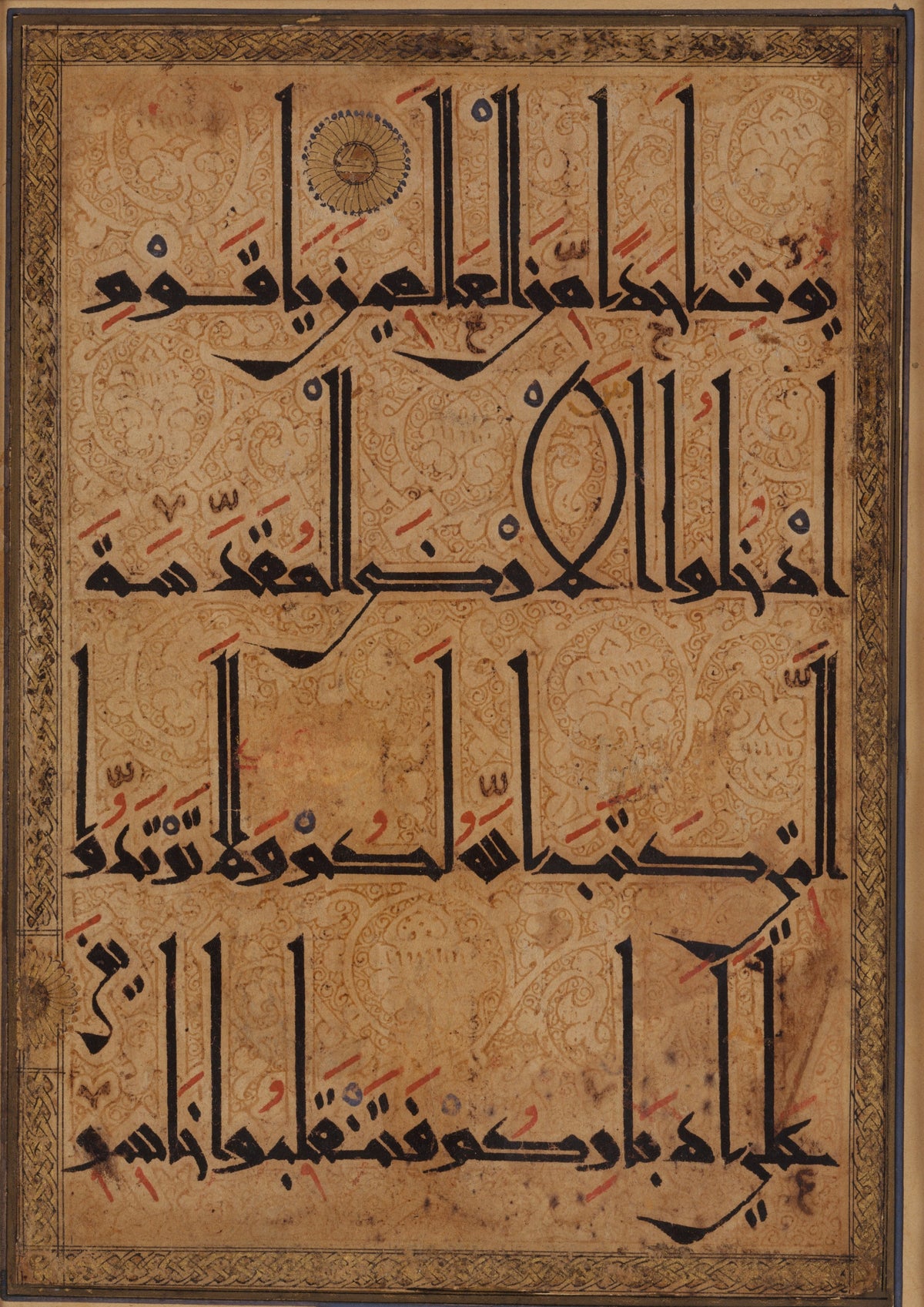 Qur'an Folio (Kufic on Scrolling Ground) — Four lines of tall black script over a ground of fine arabesques