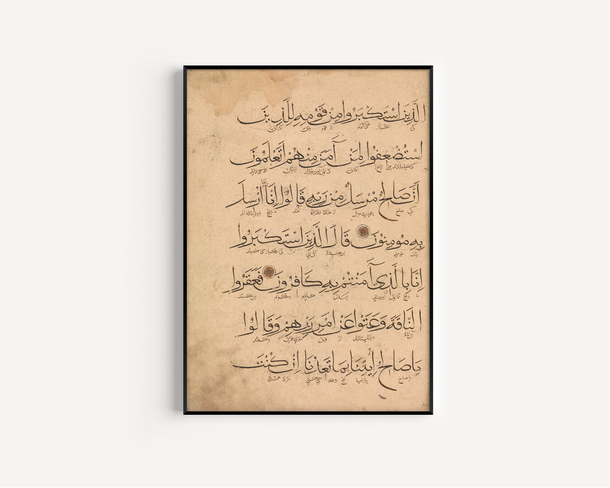 Framed art print of Qur'an Folio (Large Script with Fine Lines Beneath), in a slim black frame on a plain white wall
